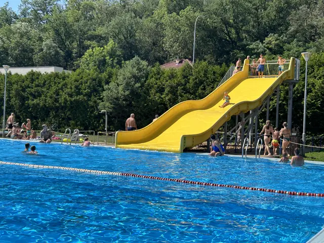 Žlutá vodní skluzavka v bazénu ve Zdicích s lidmi.