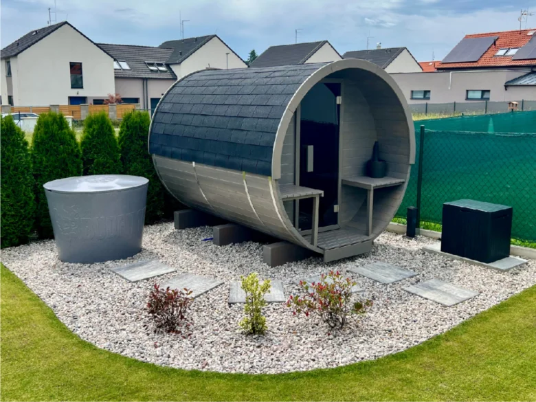Moderní zahradní sauna v kamenném terénu vedle horké vaničky.