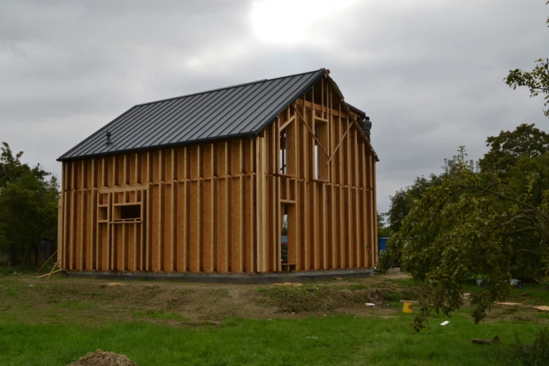 Dřevěná konstrukce domu v procesu stavby s kovovou střechou.
