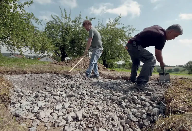 Dva muži připravují příkop pro betonování základů.