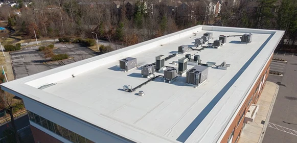 Bílá PVC fólie na ploché střeše budovy s technickým zařízením.