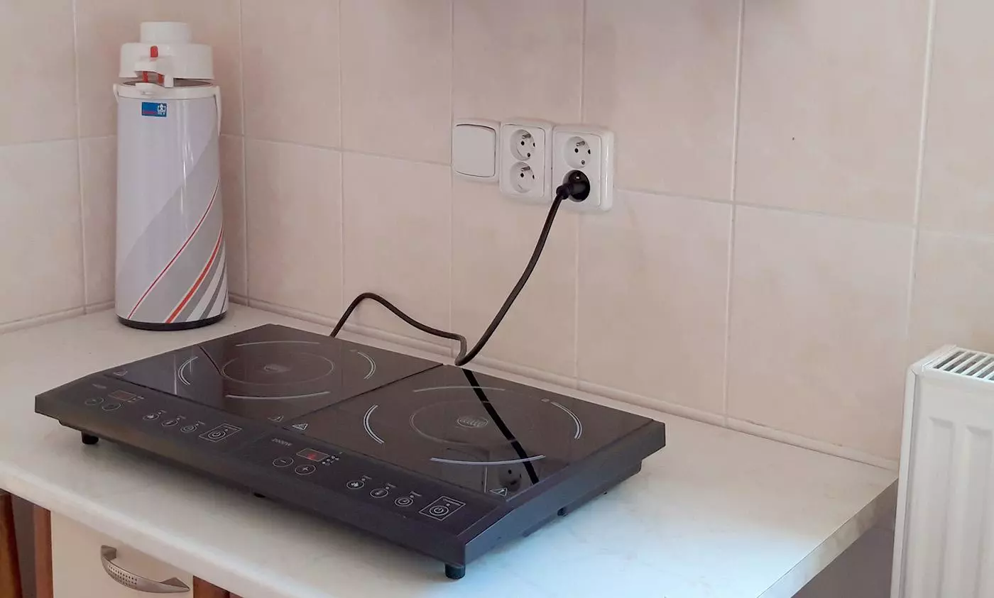 Indukční varná deska zapojená do elektrické zásuvky v kuchyni
