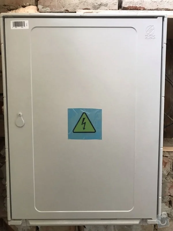 Šedý elektrický rozvaděč s varovným symbolem pro elektro služby v Olomouci.