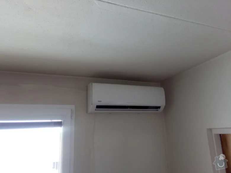 Bílá stěnová klimatizace uvnitř místnosti vhodná pro servis a čištění.