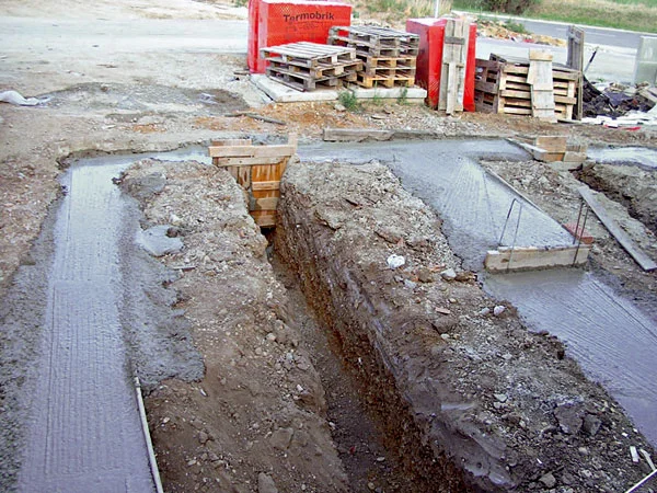 Základy budovy s vykopanými jámy pro betonáž.
