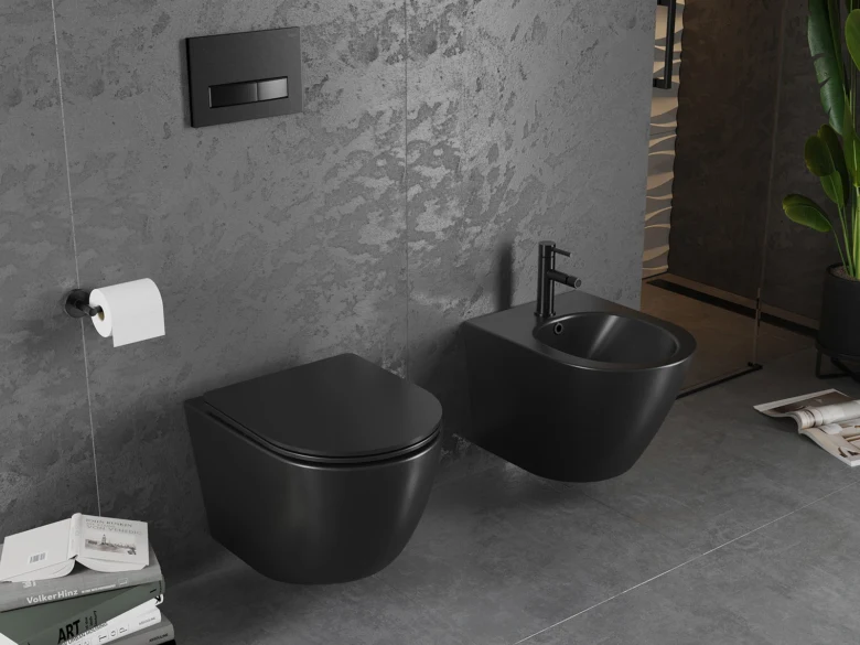 Černý bidet vedle zdi s WC v šedé koupelně.