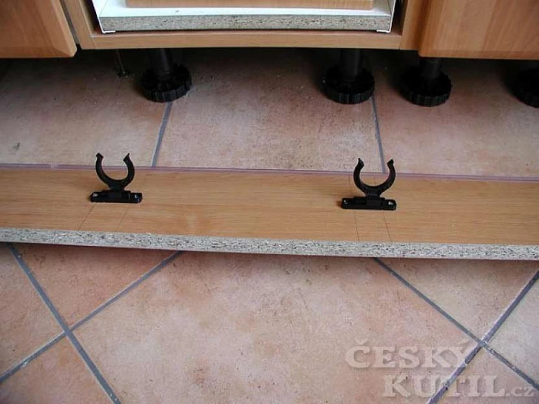 Černé montážní držáky pod dřevěnou kuchyňskou skříni.
