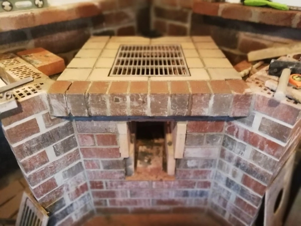 Stavba kamenného grilu s dlažbou a mříží pro zahradní krb.