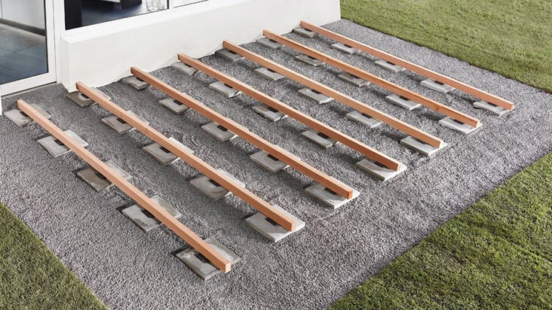Sestavení dřevěné terasy s betonovými bloky a trámy na štěrku