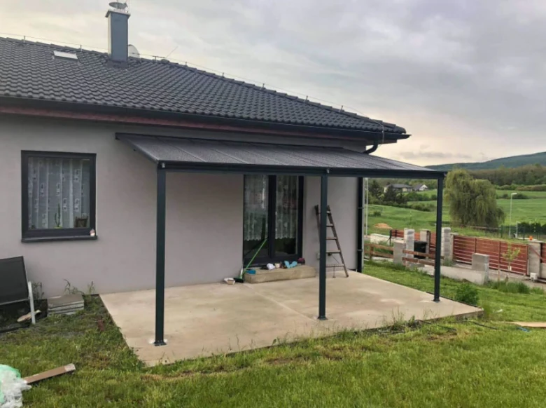 Nová hliníková pergola na terase domu v přírodě.
