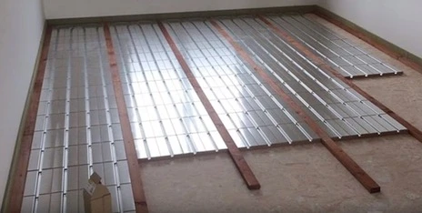 Instalace podlahového vytápění s použitím lišt na potrubí.