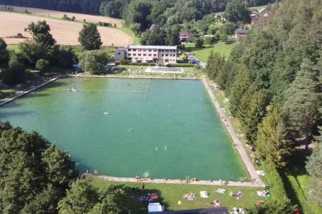 Venkovní bazén v Jeseníkách s plavci na slunci.