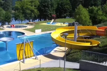 Venkovní bazén s žlutými vodními skluzavkami v Bojkovicích.