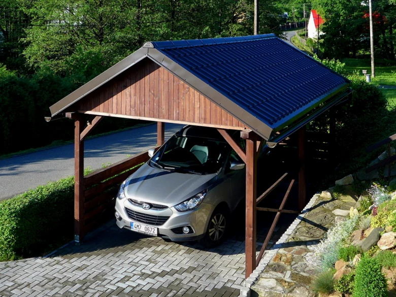 Dřevěný přístřešek pro auto s solární střechou na zahradě.