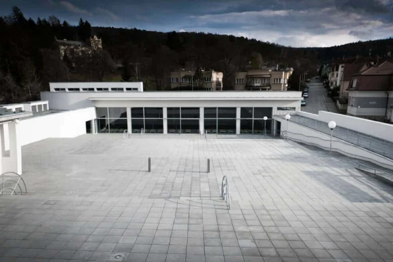 Moderní bazén v Luhačovicích nebo Pozlovicích s bílou střechou.