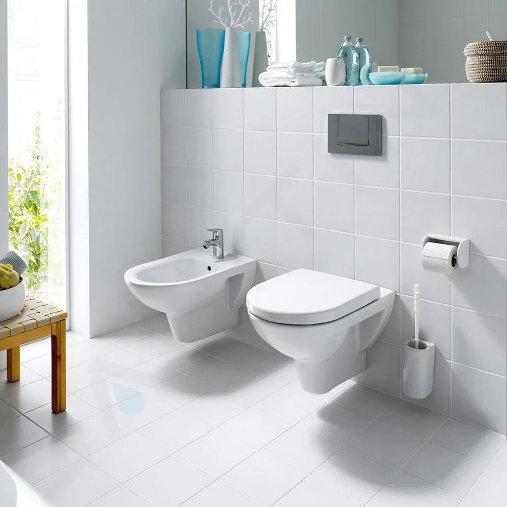 Bidet nainstalovaný vedle zdi s toaletou v bílé koupelně.