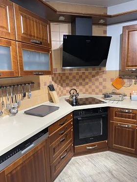 Moderní kuchyň s dřevěnými skříněmi a bílou pracovní deskou.