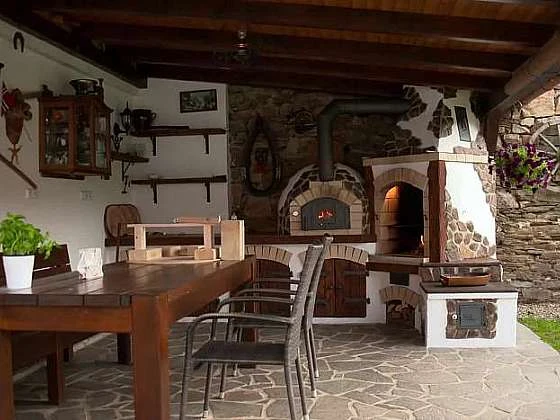 Venkovní kuchyně s kamennými pece na pizzu pod střechou.