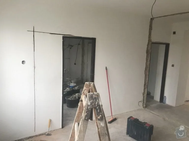 Byt v rekonstrukci s leštěnou stěnou a nářadím na podlaze.