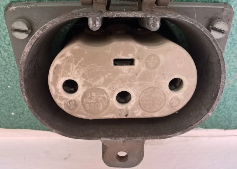 Průmyslová elektrická zásuvka s třemi kontakty pro domácí instalaci.