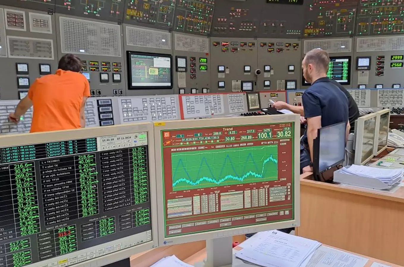 Ovládací místnost jaderné elektrárny s operátory sledujícími monitorovací systémy.