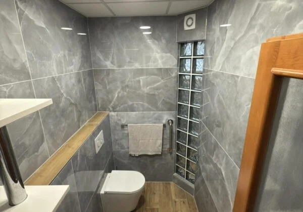 Moderní koupelna s mramorovými dlaždicemi a dřevěnými prvky.
