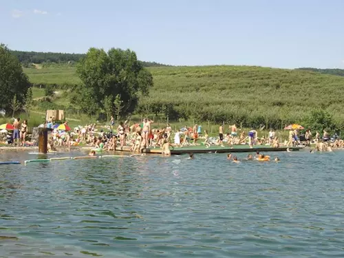 Přírodní koupaliště na jižní Moravě s lidmi v vodě.