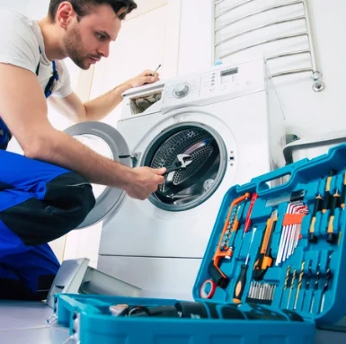 Mechanik opravuje pračku s otevřeným nádrží v domácnosti.