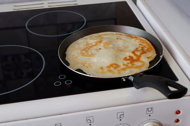 Pán s palačinkou na elektrickém indukčním sporáku.