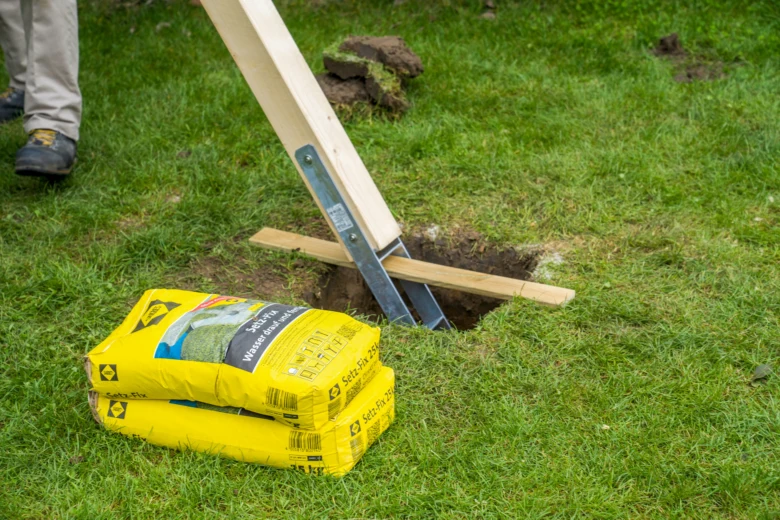 Stavební materiály pro zahradní houpačku s dřevem a betonovou směsí.