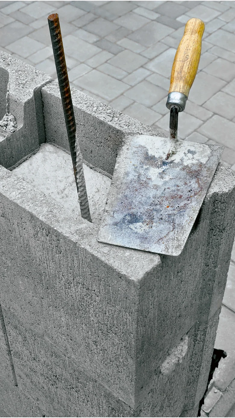 Kamenný blok s výztuží a špachtlí na staveništi.