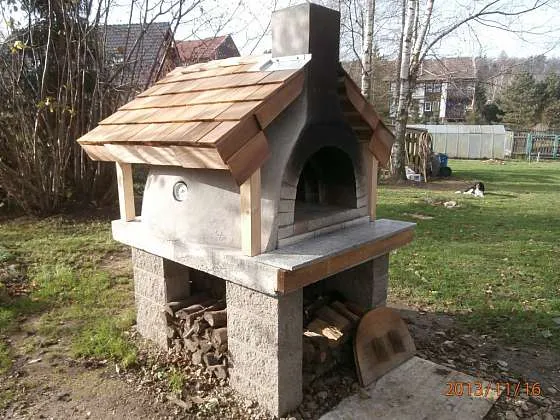Samostatná venkovní pec na pizzu z cihel s dřevěnou střechou.